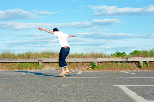 A man rides his longboard by the beach.