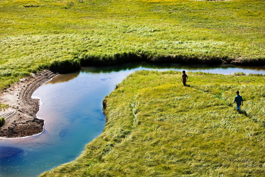 Two young men hike through a grassy field in Yellowstone National Park, Montana.