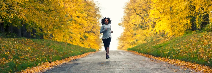 Gordijnen Woman jogging on country road in Autumn © Darren Baker