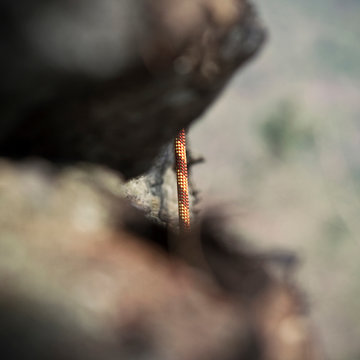 A detail of a climbing rope on the side of a cliff.