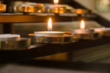 Votive candles lit as prayers for loved ones inside a Christian church setting