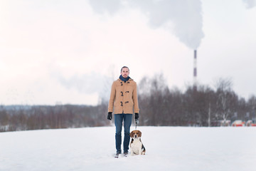 Cheerful man with standing with a dog on a meadow in winter