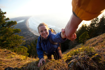 One person helping another up steep section of trail while hiking