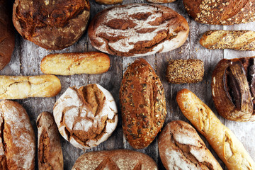 Different kinds of bread and bread rolls on board from above. Kitchen or bakery