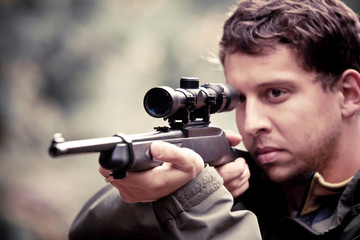 Male hunter aiming with rifle