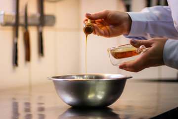 The chef cooking chicken wings in a sauce in the kitchen. Decorating the dishes with colored blobs. Lymon. Chicken. Sauce with honey and seasonings