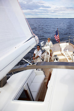 A woman is at the helm of luxury sailing yacht "Isobel" as she cruises off the coast of Maine. "Isobel" is a 75' cold-molded Spirit of Tradition yacht, designed by Stephens & Waring Yacht Design and built by Brooklin Boatyard, Maine.