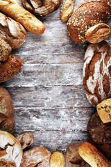 Different kinds of bread and bread rolls on board from above. Kitchen or bakery