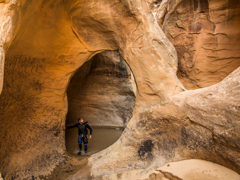 Eric Odenthal canyoneering and standing in a natural rock arch in Segers Hole canyon, San Rafael Swell, Utah.