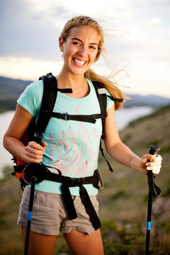 Melissa Lombardi, a young woman, wears a day pack and uses hiking pole as she hikes on windy day along Horestooth Reservoir, Fort Collins, Colorado.