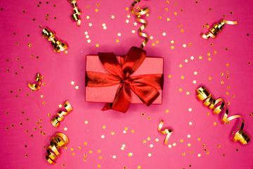 Gift box and Golden decorations and sparkles on bright  pink background