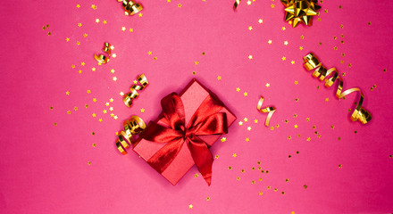 Gift box and Golden decorations and sparkles on bright  pink background