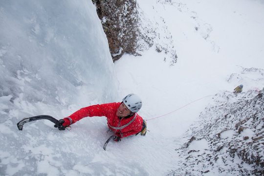 Zach Fletcher lead climbing water ice in wintery conditions while Todd Offenbacher belays below at Red Cliffs in Kirkwood, California.