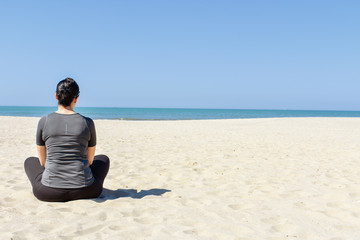 Fototapeta na wymiar woman sitting on beach and looking at the sea
