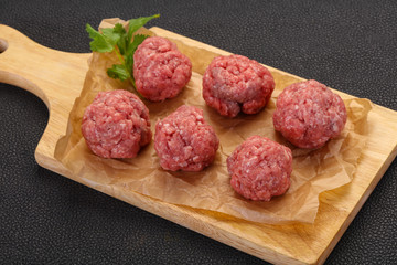 Raw meatball over wooden background