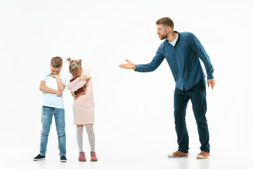 Angry father scolding his son and daughter at home. Studio shot of emotional family. Human emotions, childhood, problems, conflict, domestic life, relationship concept