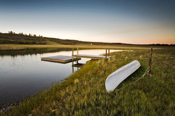 A pond, canoe, raft, and dock at dusk on the Uncompahgre plateau, Colorado. (release code: NCreekRanch)