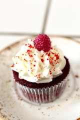 Tasty red velvet delicious sponge cupcake with white butter cream frosting and  raspberrie on plate. Candy bar for celebrating partys and birthdays