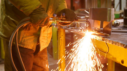 Construction plant. A man at his workplace using a welding machine. Heating up the side of the...