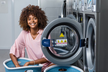 Young black African American woman washing her clothes in a automatic laundry