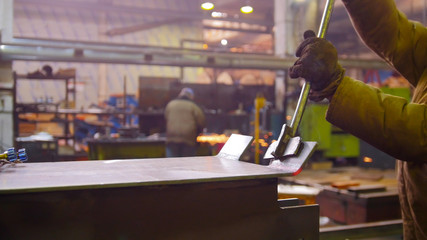 Construction plant. A worker bending the heated detail