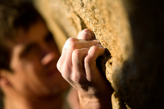 Climber grimacing as he grips onto hold