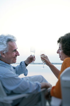 A couple in their 50's laugh and celebrate life on a boat dock overlooking the Chesapeake Bay at sunset near St. Michael's, Maryland.  (releasecode: CM_MR1004, MR_MR1005)