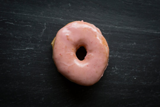 A donut sits on a cutting stone.