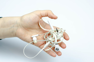 tangled white no brand earphones in a hand on white