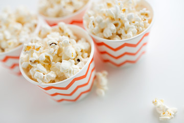 fast food, junk-food and unhealthy eating concept - close up of popcorn in disposable paper cups with zig zag pattern
