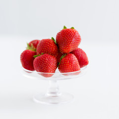 fruit, food and berries concept - strawberries on glass stand over white background