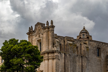 Fototapeta na wymiar Church tower, roof and entry arch of Chiesa di Sant'Agostino, view of ancient town of Matera, Basilicata, Southern Italy, cloudy summer warm August day