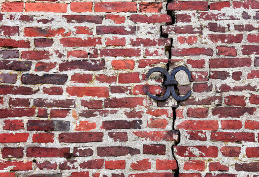 background of an old brick wall with a crack and an iron bracket that acts as a screed and thus strengthens the structure. © dinanana