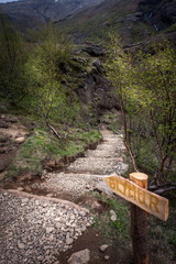 Beautiful landscape with a sign pointing to the stairs among the vegetation leading to the waterfall - Glymur, Iceland