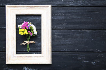 Spring flowers with frame on black wooden table