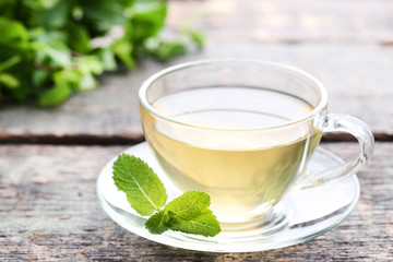Cup of tea with mint leafs on wooden table