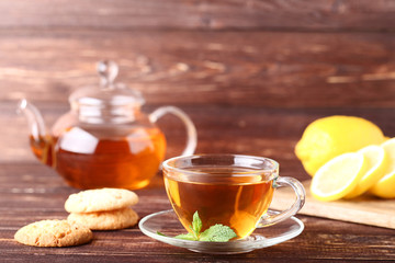 Cup of tea with cookies and mint leafs on wooden table
