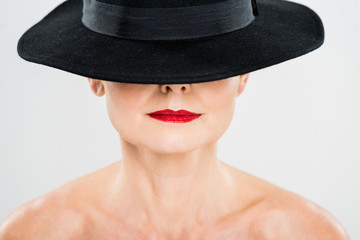 middle aged elegant and fashionable woman with red lips in black hat isolated on grey