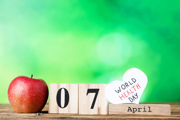 Text World Health Day with red apple and cube calendar on green background