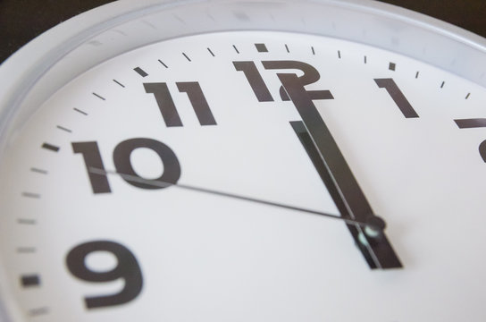 Macro photo of a black and white clock from 12 o'clock. Time concept