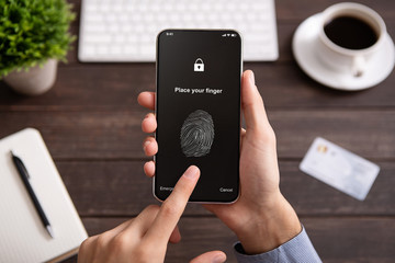 Hand holding mobile phone with application for scanning fingerprint