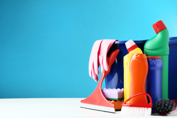 Bottles with detergent and cleaning tools on blue background