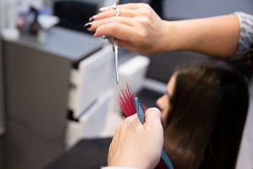 Woman hairdresser cutting customer hair with scissors.