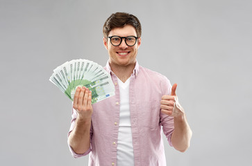 money, finance, business and people concept - happy young man in glasses with fan of one hundred...