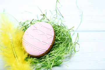 Easter gingerbread cookie with yellow feather on wooden table