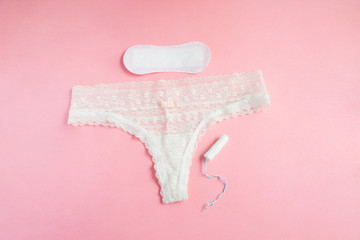 women intimate hygiene products - sanitary pads and tampon near womans panties on pink background