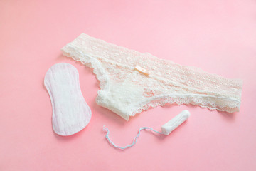 Fototapeta na wymiar women intimate hygiene products - sanitary pads and tampon near womans panties on pink background