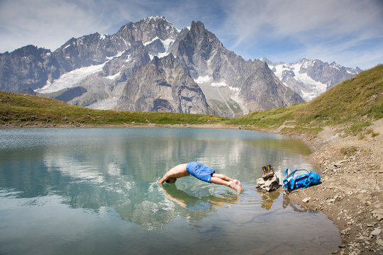 A male hiker is taking a bath in a mountain lake near Courmayeur in the Italian Alps, with Mont Blanc in the back ground.
