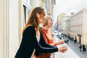Portrait of two pretty blonds women, mother and daughter, drinking tea. Mature middle age and adult...