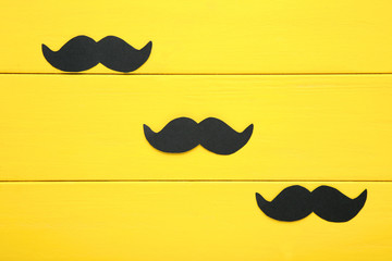 Paper mustache on yellow wooden table